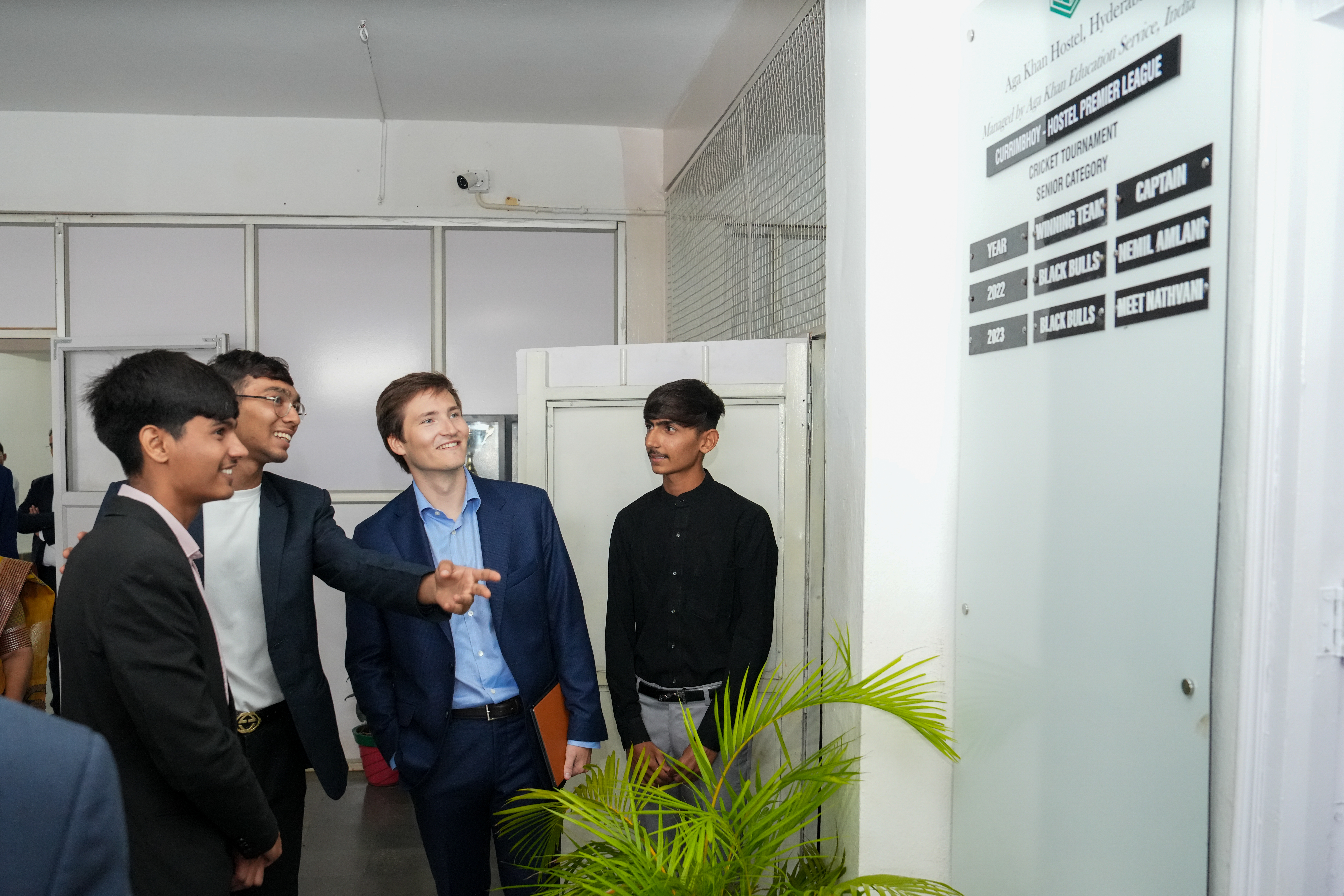Prince Aly Muhammad Aga Khan looking at a board with students from the Aga Khan Hostel, Hyderabad